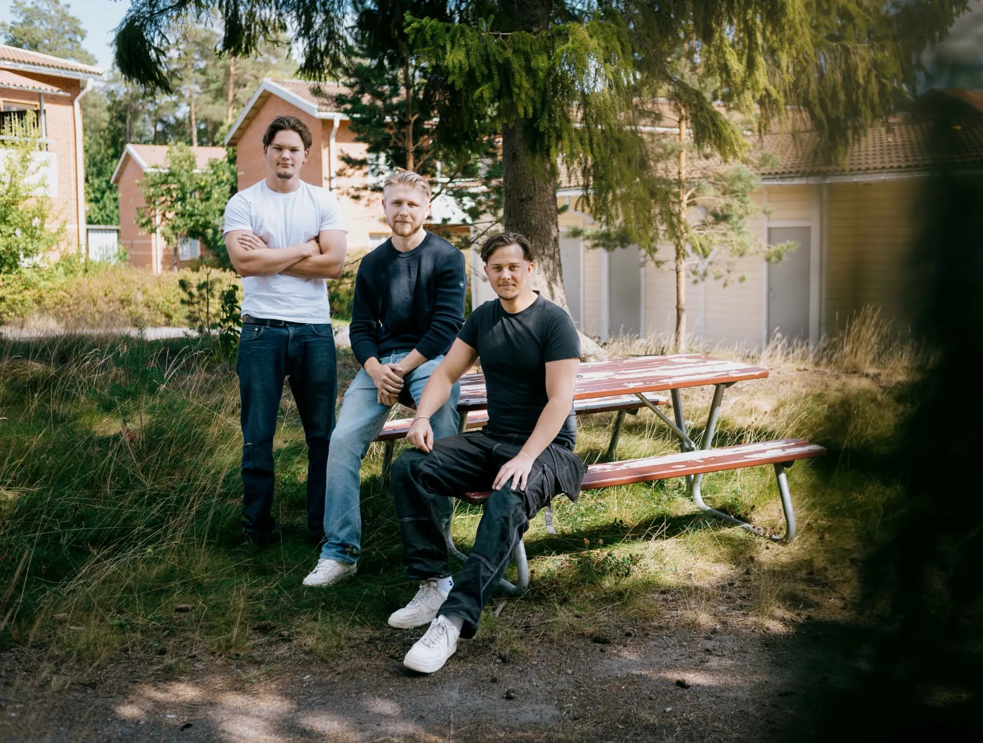 Tre personer från Bark & Bo vid en bänk i en grön gård